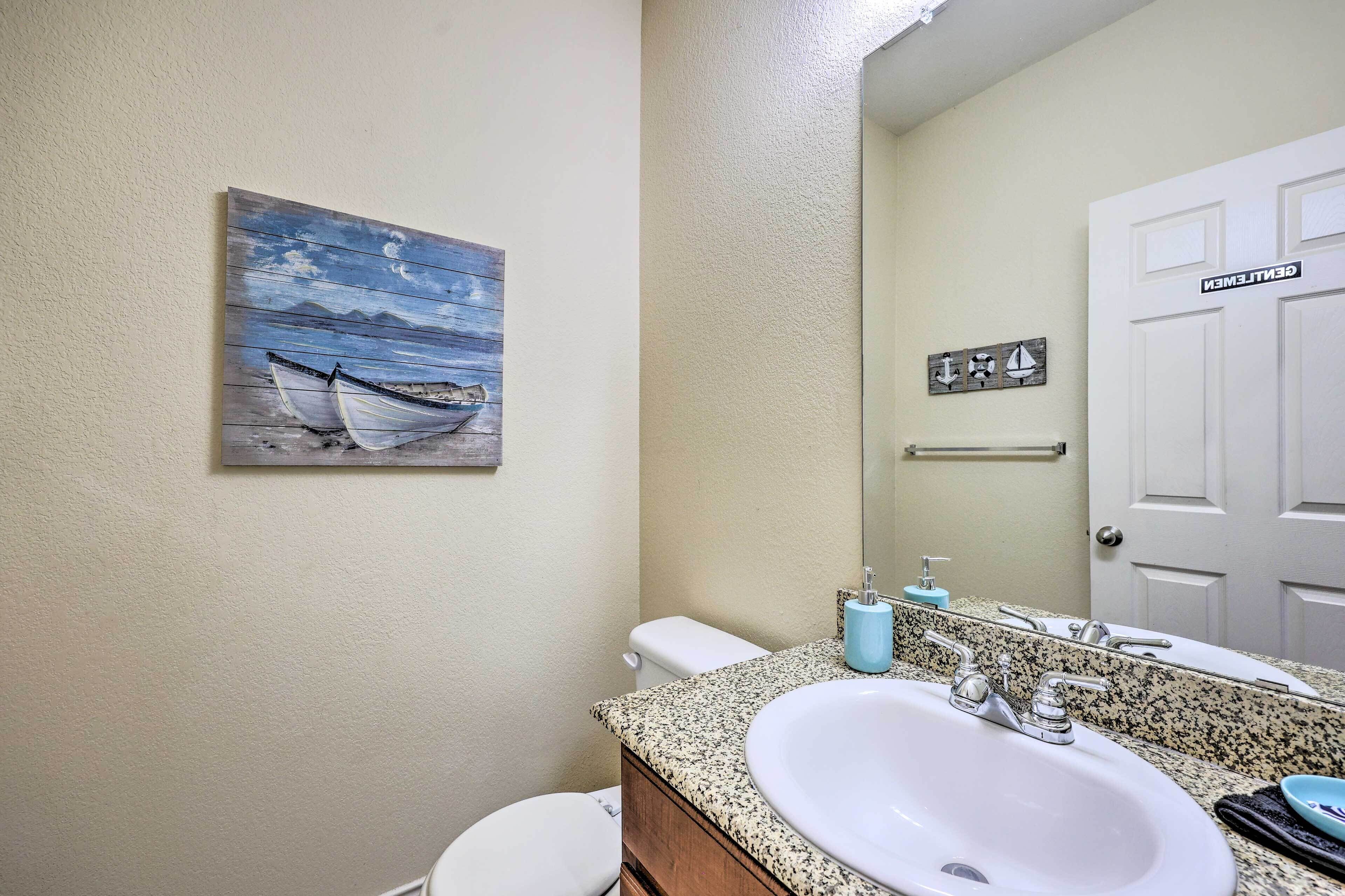 A bathroom with a white sink, a mirror, and a painting of boats on the wall.