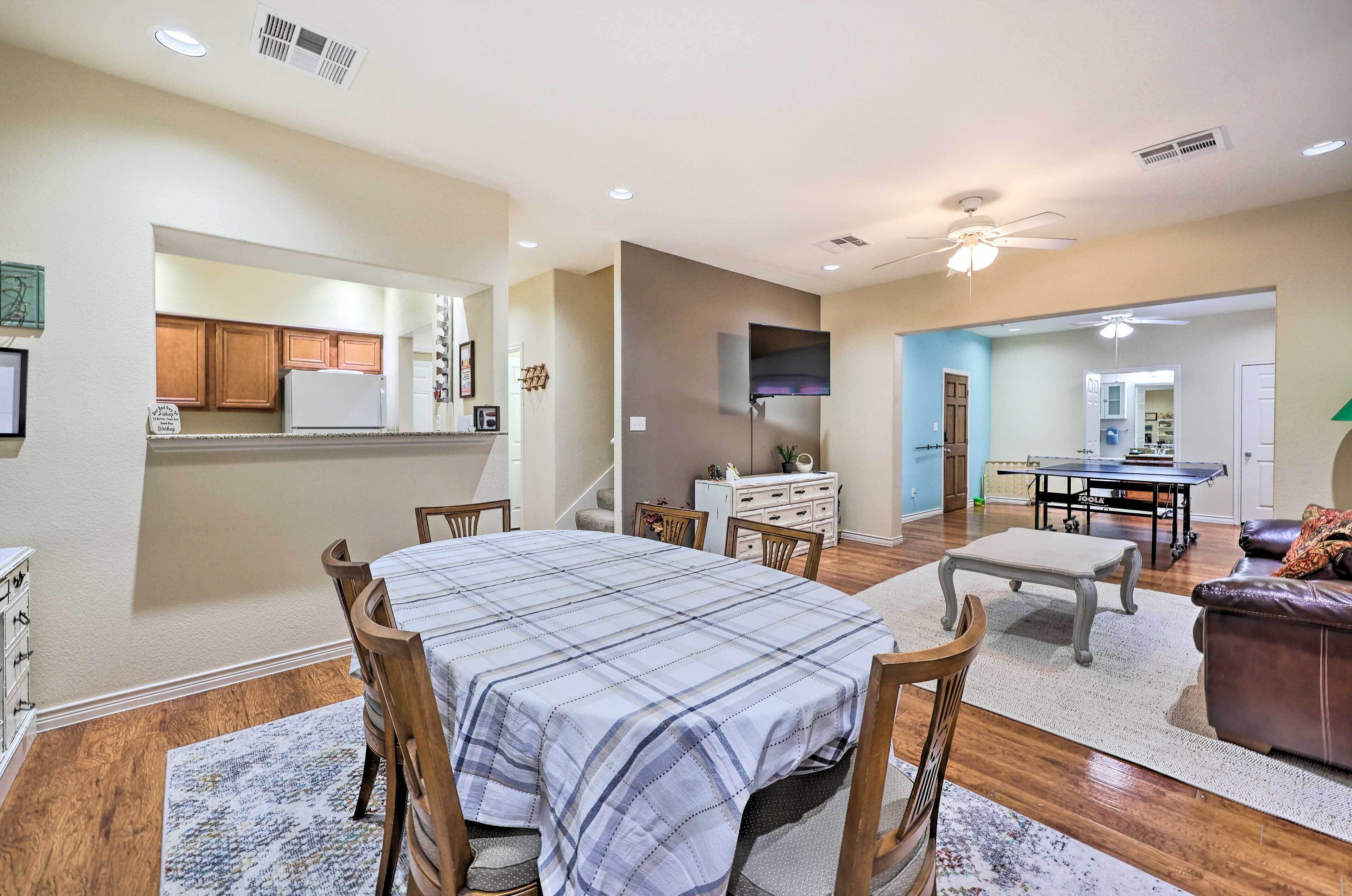 A spacious living room with a dining area, wooden flooring, and a ceiling fan.