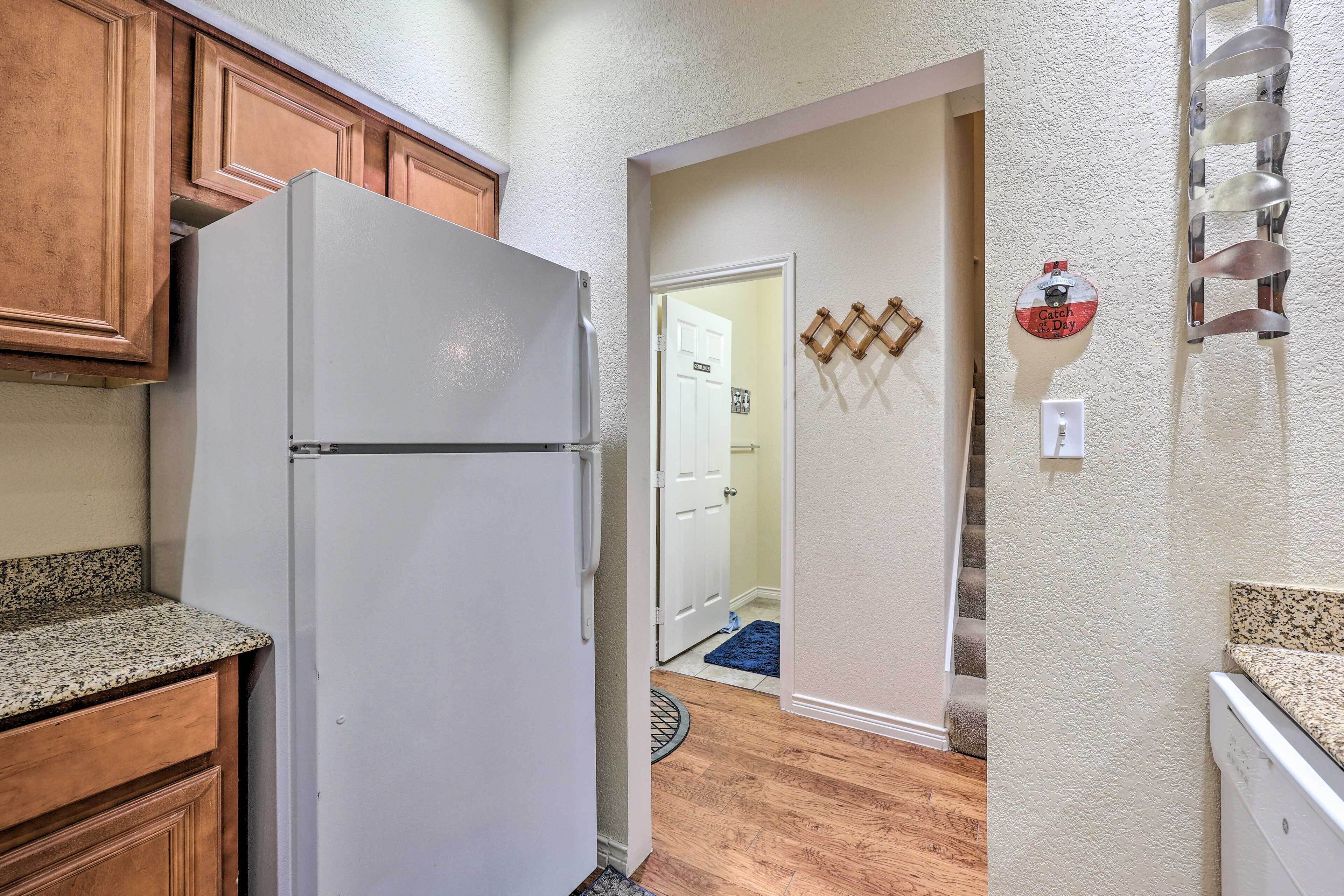 A kitchen with wooden cabinets, a white refrigerator, and a granite countertop.