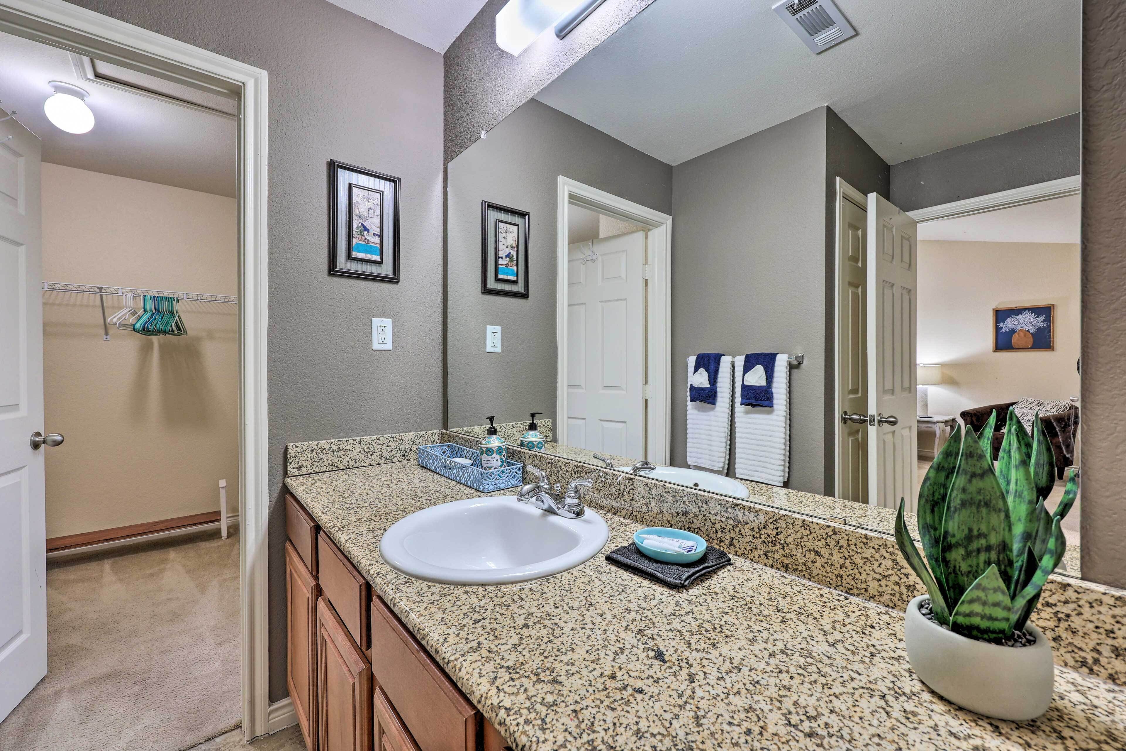 A bathroom with a granite countertop, white sink, and a potted plant.