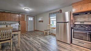 A kitchen with wooden cabinets, stainless steel appliances, and a dining area with a wooden table and chairs. - Cozy Goshen Farmhouse ~ 9 Mi to Amish Acres (Goshen)