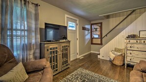 A living room with a sofa, a cabinet, a television, and a staircase. - Cozy Goshen Farmhouse ~ 9 Mi to Amish Acres (Goshen)