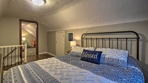 A bedroom with a bed, a headboard, a nightstand, a lamp, a mirror, and a door leading to another room. - Cozy Goshen Farmhouse ~ 9 Mi to Amish Acres (Goshen)