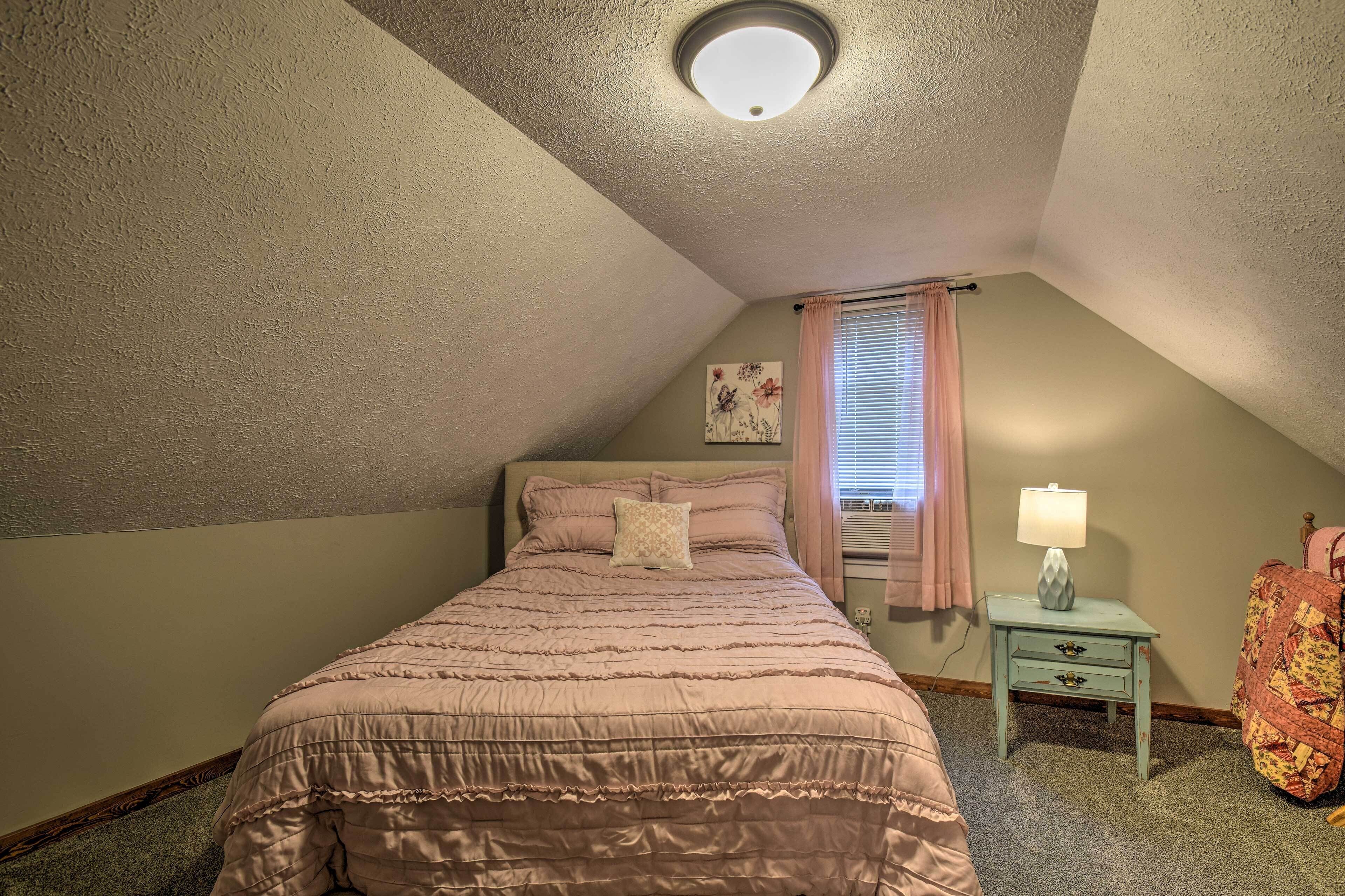 Een slaapkamer met een enkel bed, een nachtkastje met een lamp, een raam met gordijnen en een wand met een bloemverfijng.