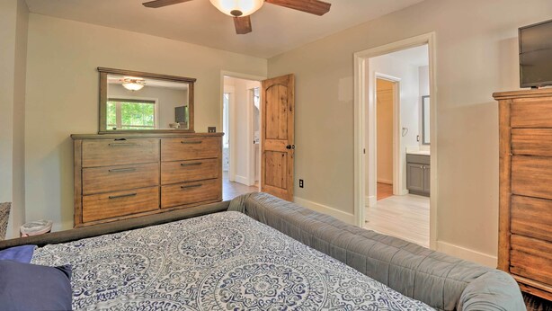 A bedroom with a bed, a wooden dresser, a ceiling fan, and a door leading to another room. - Pet-friendly Mechanicsville Retreat w/ Deck! (Mechanicsville)
