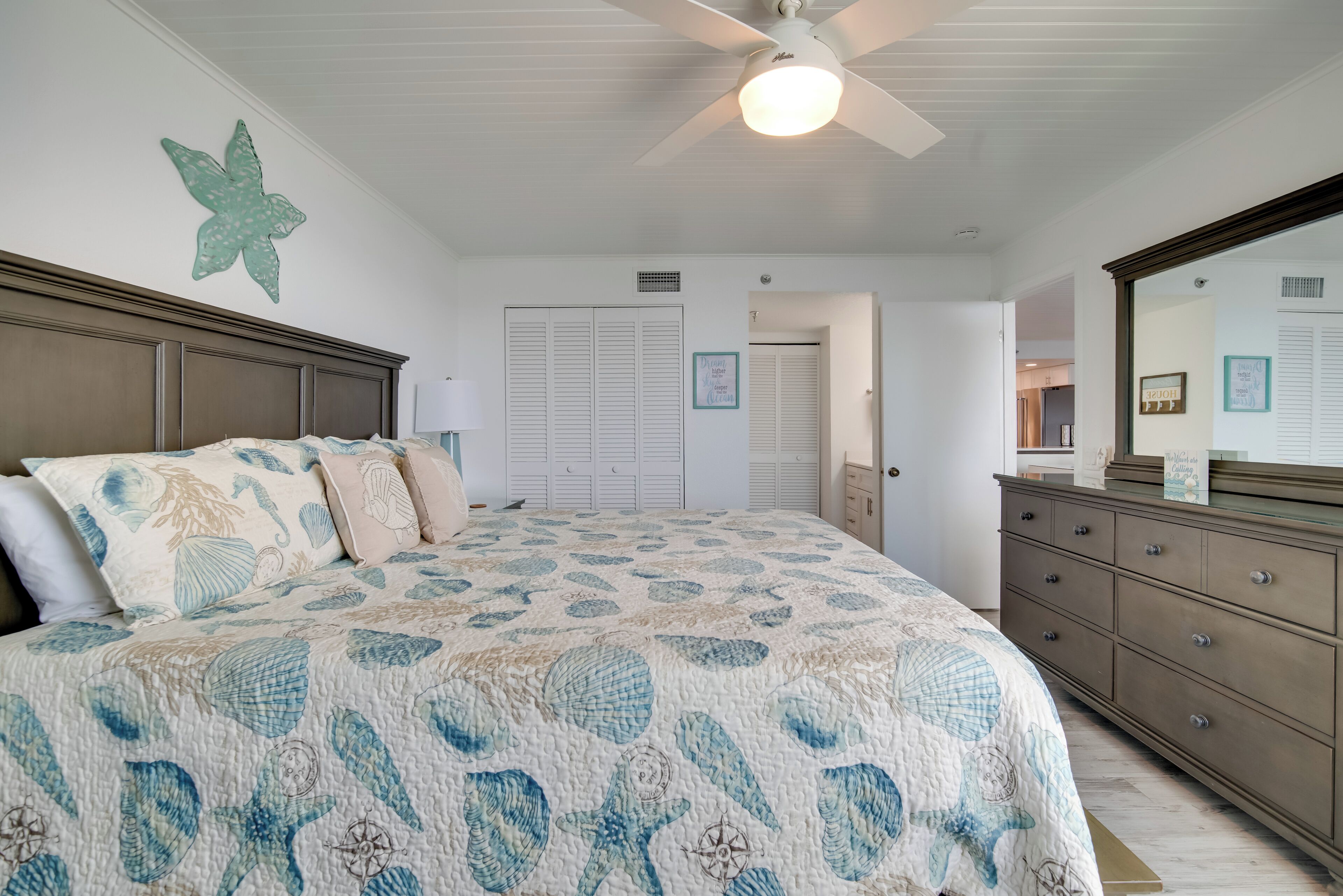 A bedroom with a bed, dresser, and a ceiling fan.