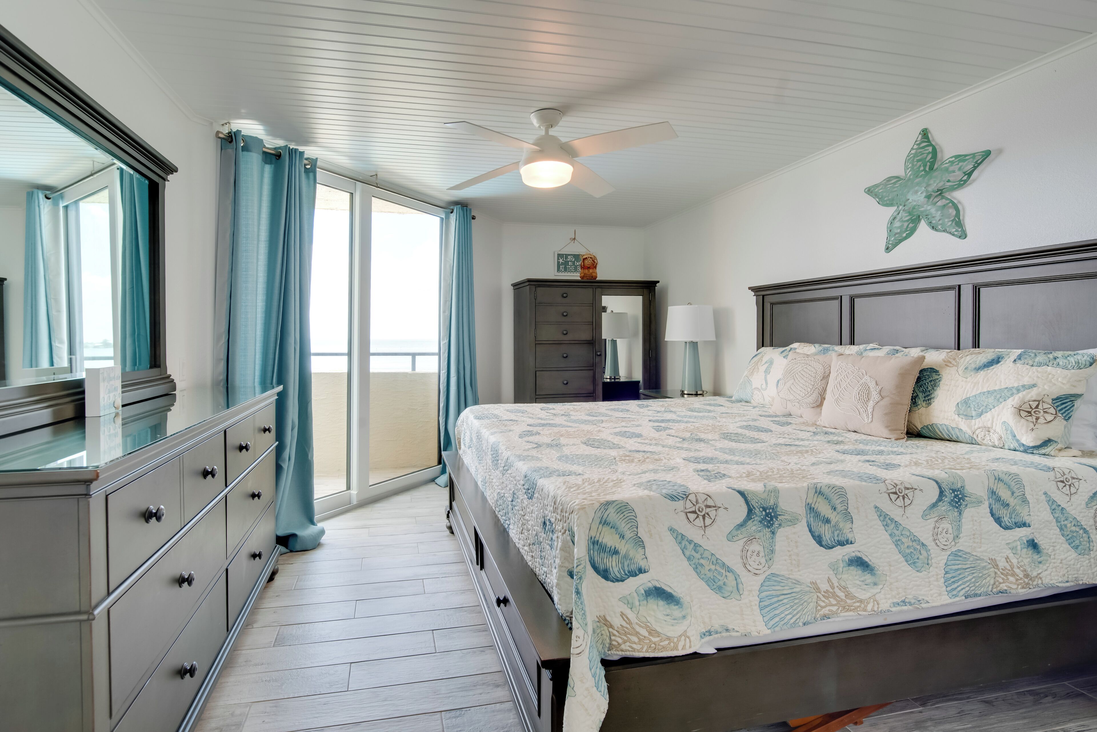 A bedroom with a bed, dresser, and a ceiling fan.