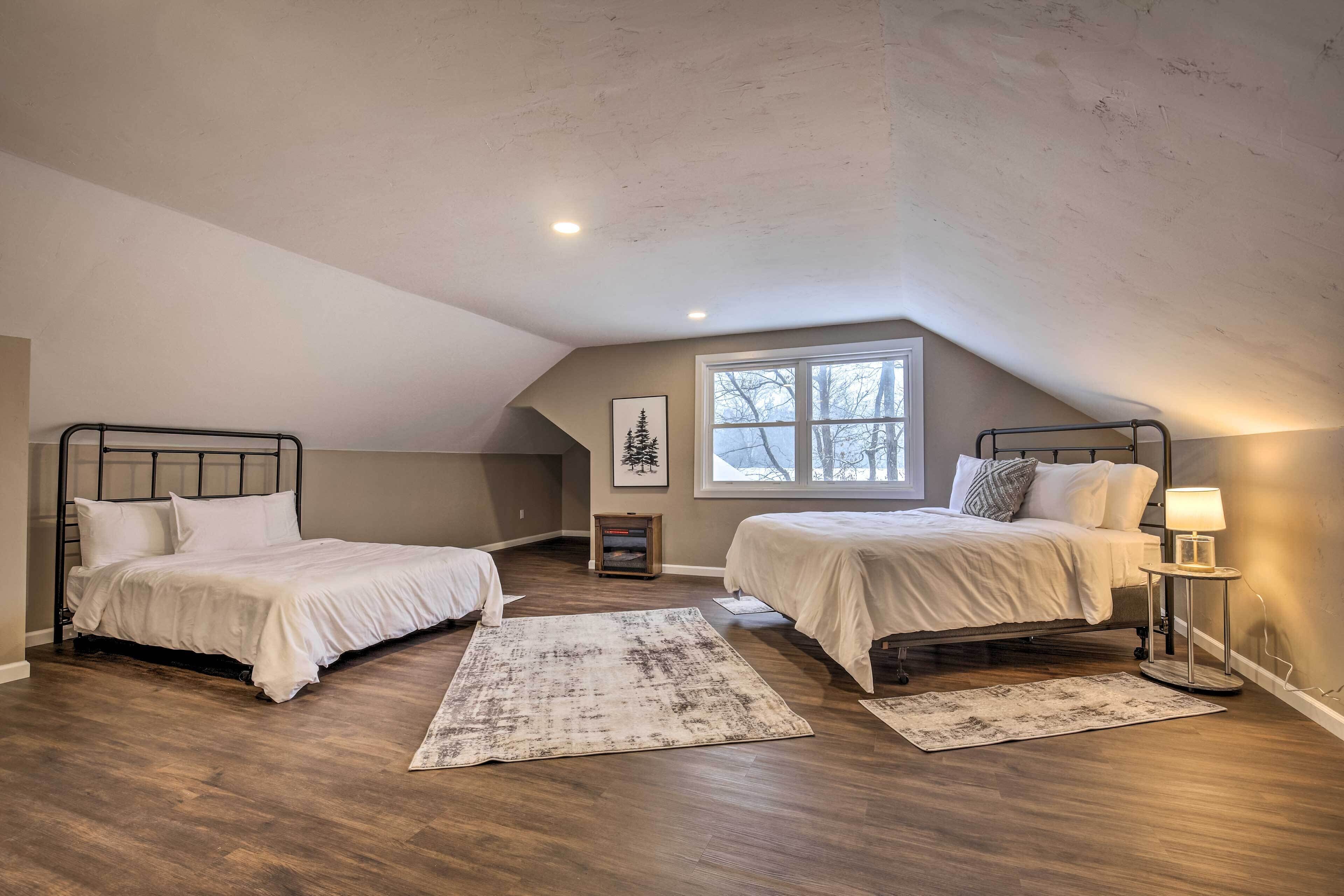 Een slaapkamer met twee bedden, een groot raam en een schuin dak.
