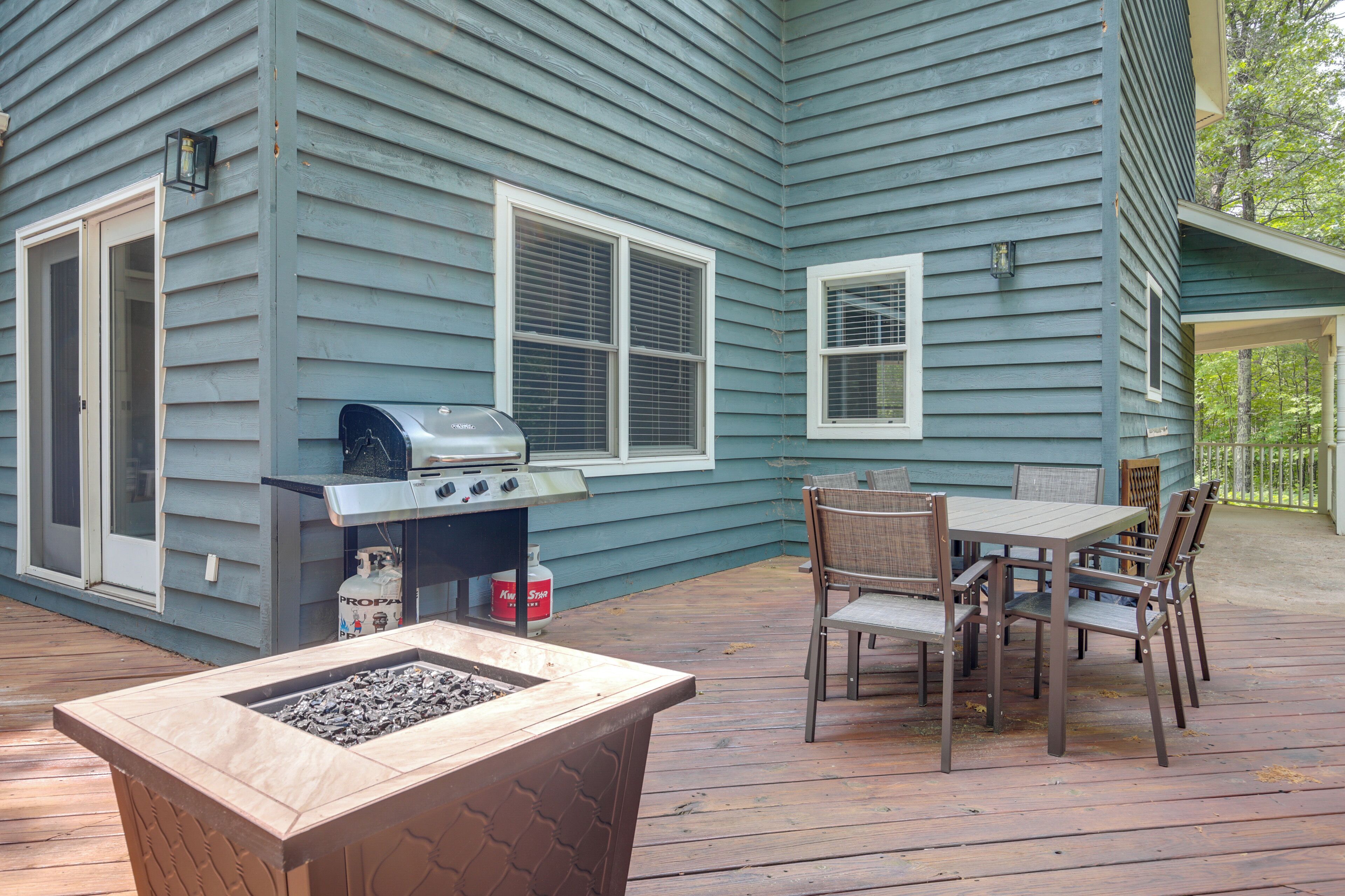 An outdoor patio with a grill, a table with chairs, and a fire pit.