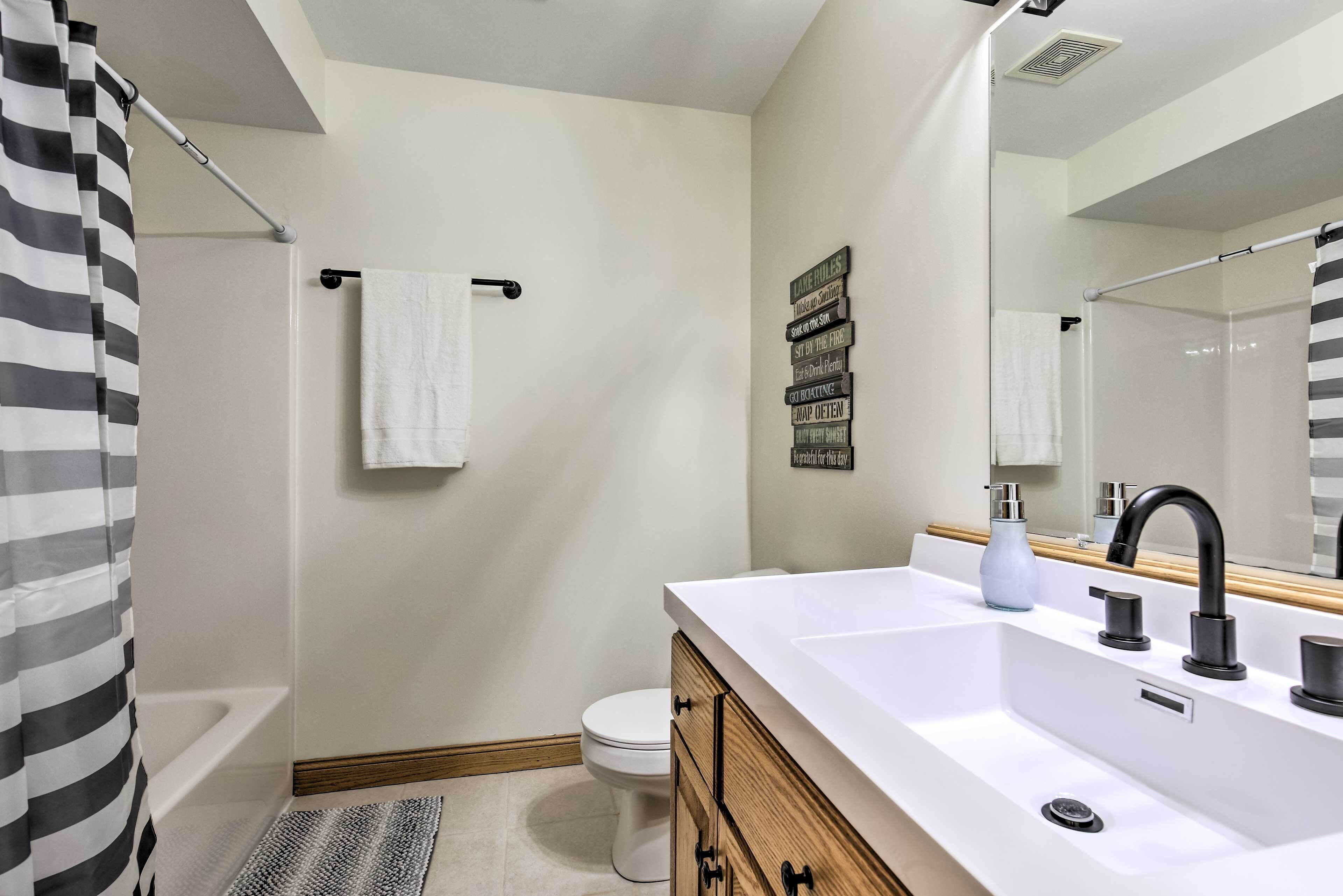 Un baño moderno con un lavamanos blanco, un grifo negro y una cortina de ducha.