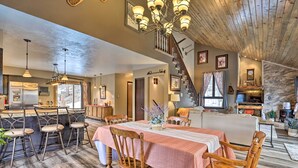A spacious living area with a wooden dining table, bar stools, and a staircase leading to an upper level. - Private Sauna & Mtn Views: Idaho Springs Gem (Idaho Springs)