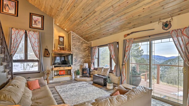A cozy living room with a stone fireplace, comfortable seating, and a television. - Private Sauna & Mtn Views: Idaho Springs Gem (Idaho Springs)