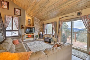 A cozy living room with a stone fireplace, comfortable seating, and a television. - Private Sauna & Mtn Views: Idaho Springs Gem (Idaho Springs)
