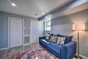 Una habitación con un sofá azul, alfombra estampada y una lámpara de pie.