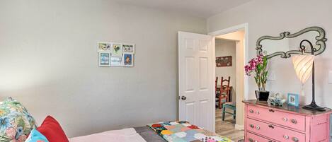 A bedroom with a bed, a dresser, a mirror, and a door leading to another room.