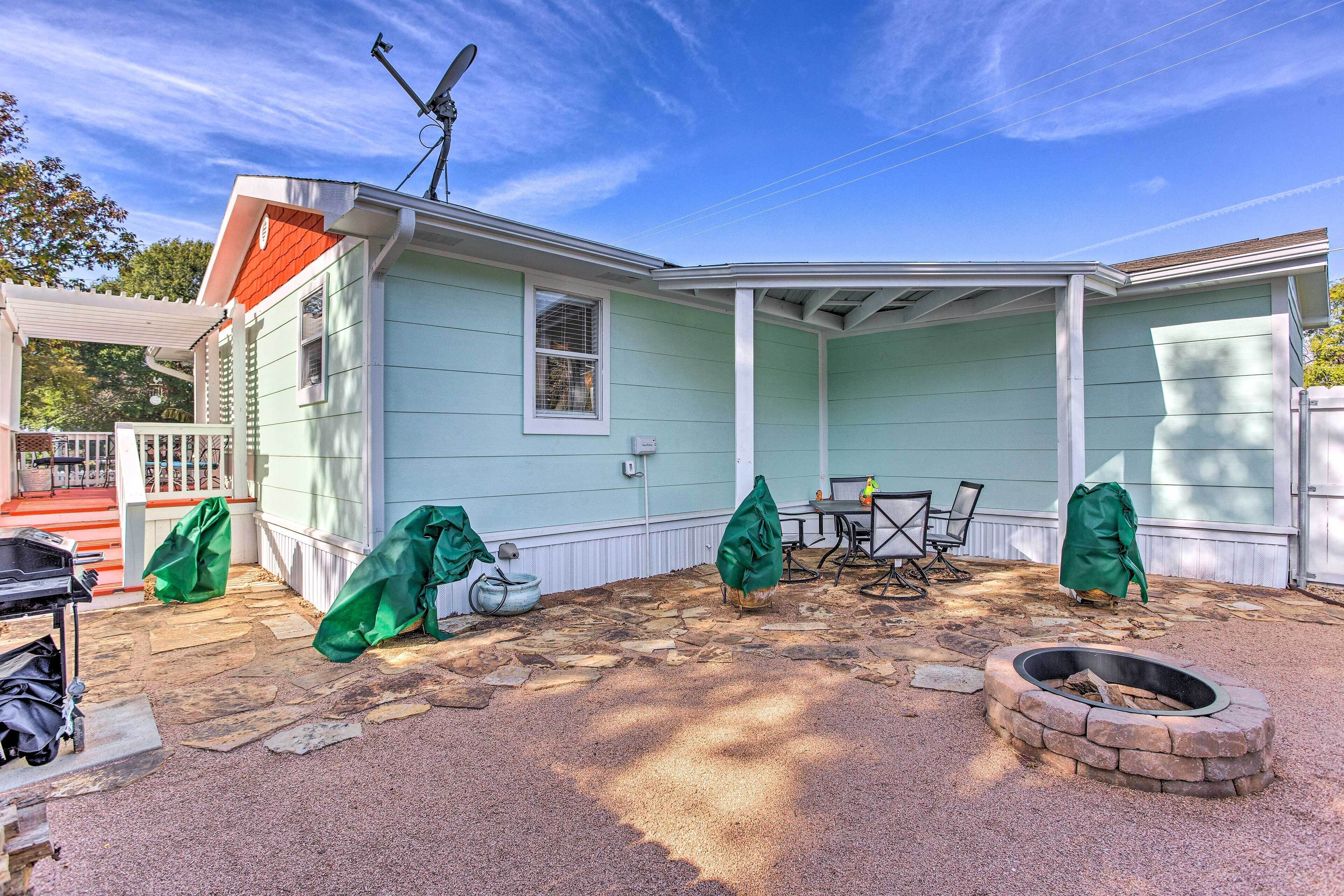 Un patio couvert avec un foyer en pierre, du mobilier d’extérieur et une pergola.