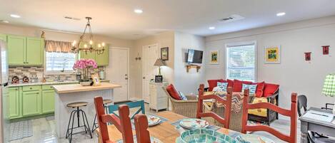A modern kitchen with green cabinets, a wooden dining table, and a central island.
