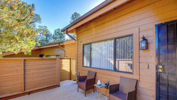 A wooden cabin with two wicker chairs and a small table outside, a black door, and a large window. - Pet-friendly Prescott Townhome w/ Fireplace! (Prescott)