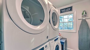 A laundry area with stacked front-loading washers and dryers, a window with a view, and a sign above the window. - Family-friendly New Bern Home w/ Backyard! (New Bern)