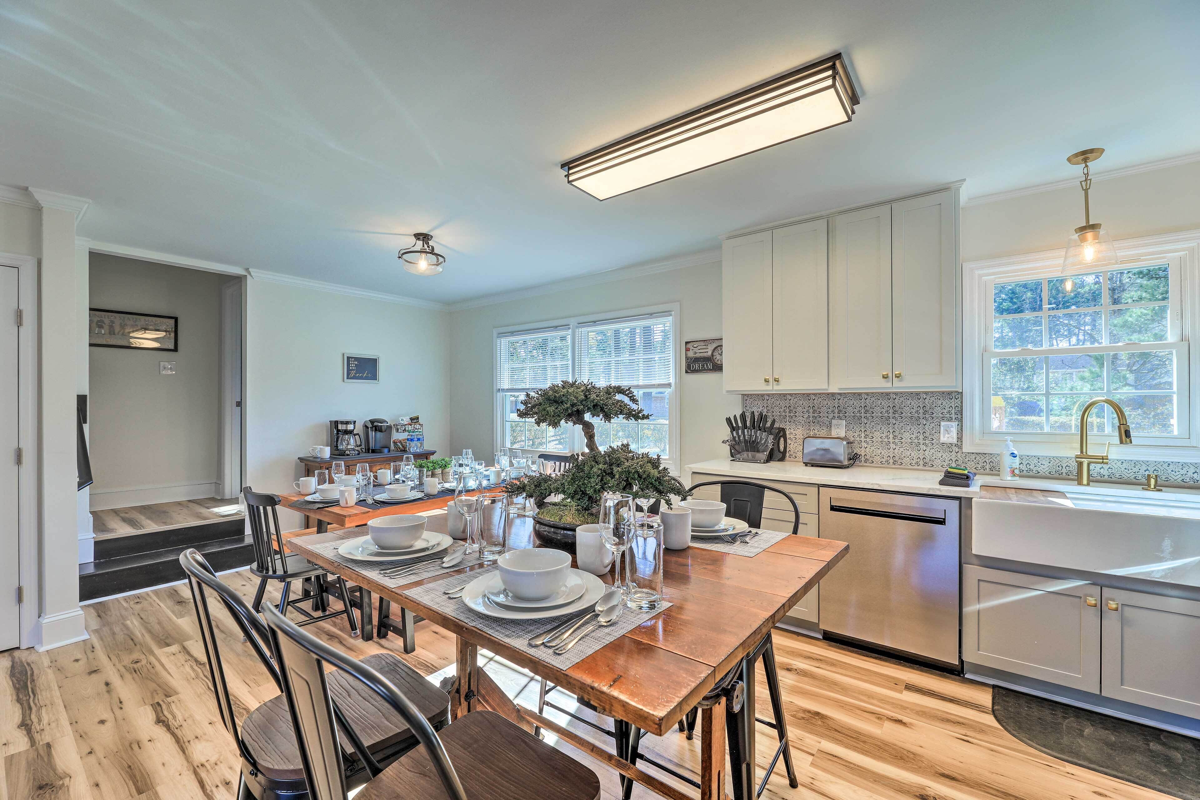 A modern kitchen with white cabinets, a built-in dishwasher, and a large window providing natural light.