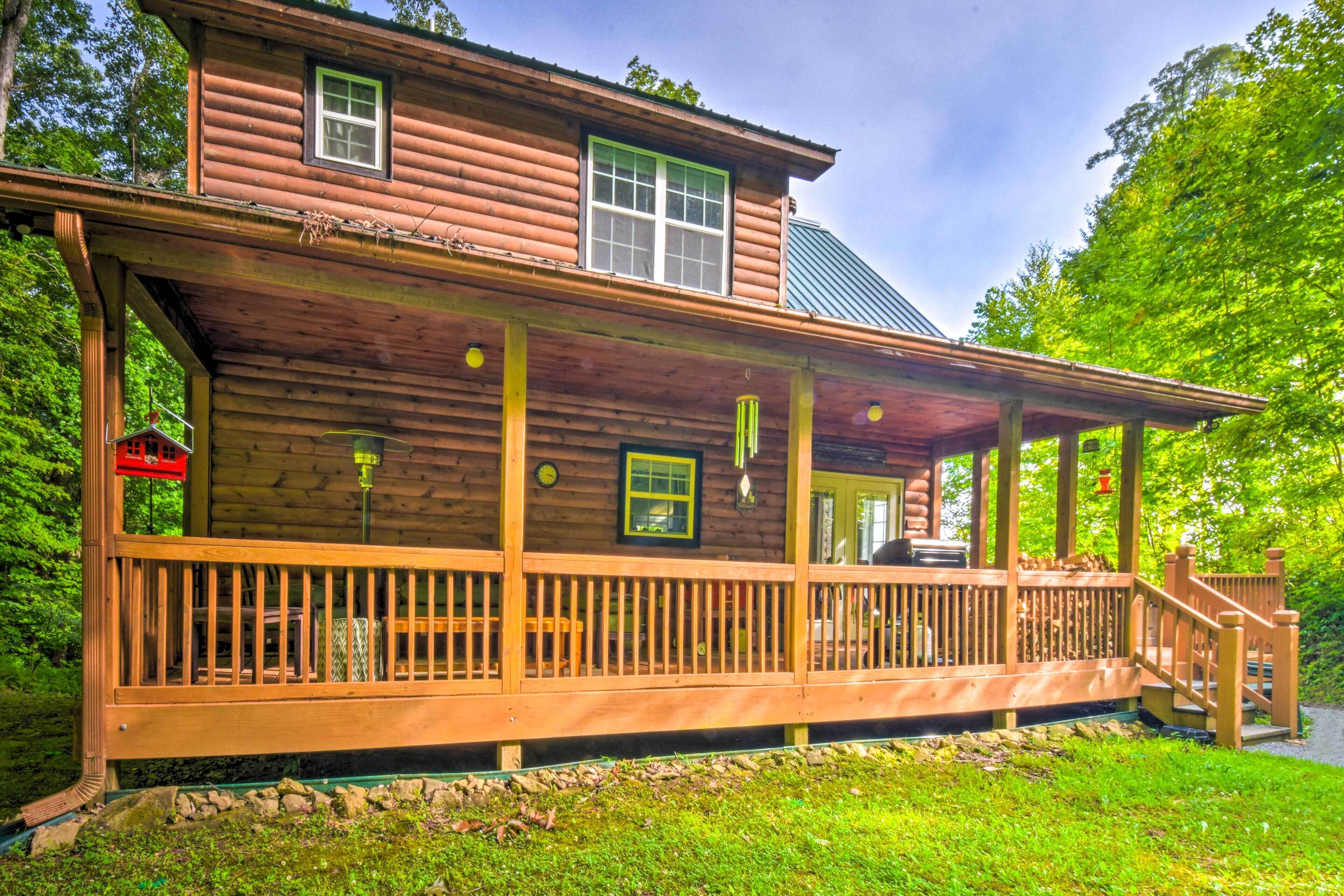 A wooden cabin with a porch, a small deck, and a covered area.
