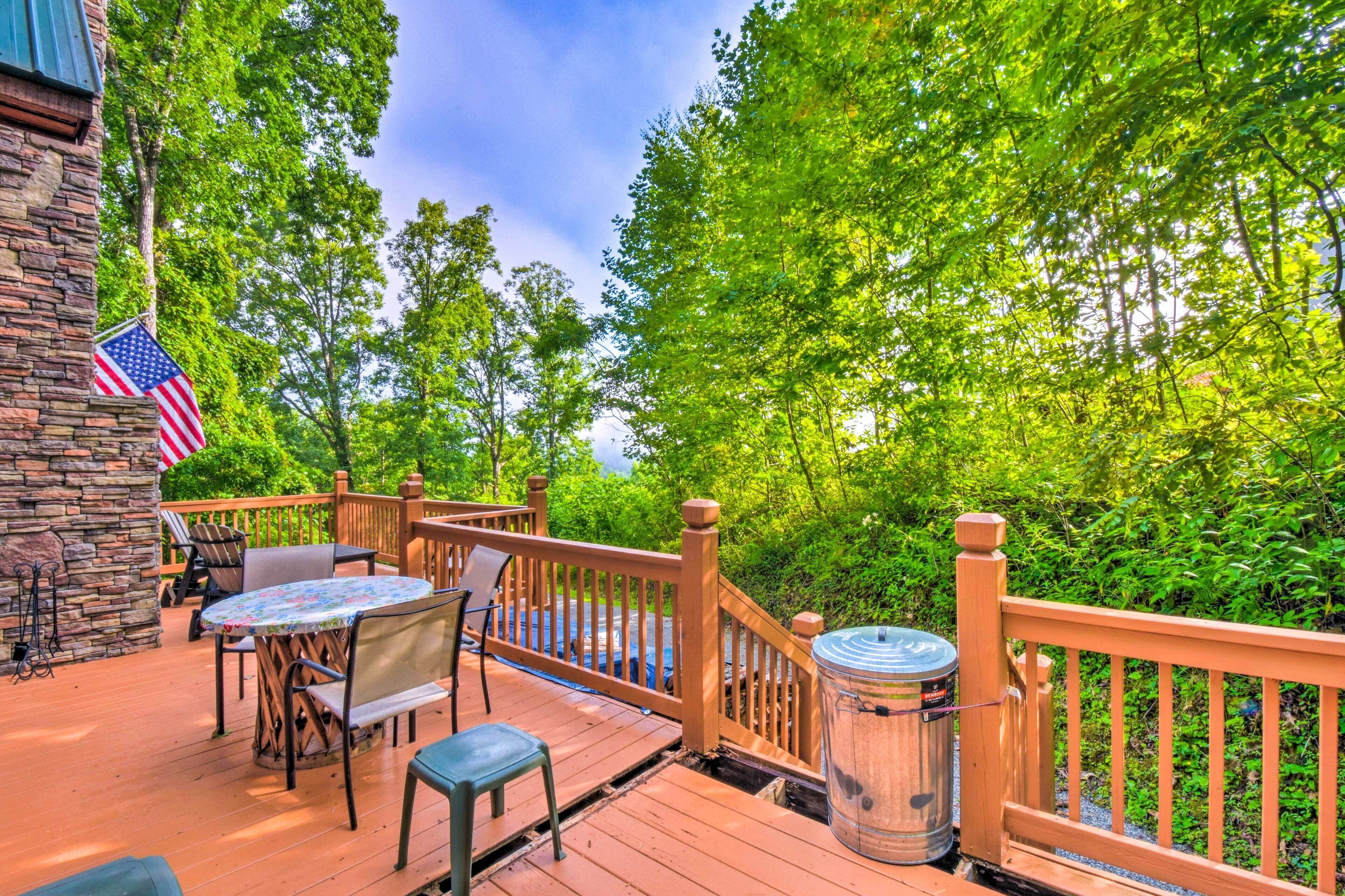 A wooden deck with outdoor furniture, a stone wall, and an American flag.