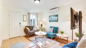 A living room with a sofa, a coffee table, a TV, and a window with curtains. - Quiet Carpinteria Cottage By Town & Beaches (Carpinteria)