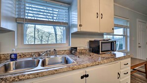 A kitchen with a double sink, a microwave, and cabinets. - Maggie Valley Cottage Near Festival Grounds! (Maggie Valley)