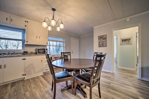 A kitchen with white cabinets, a round dining table, and a chandelier.