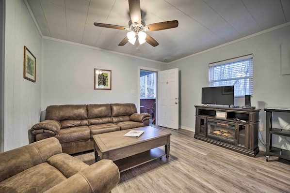 A living room with a brown leather sofa, a wooden coffee table, a fireplace, and a ceiling fan.