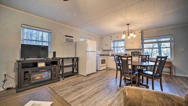 A modern kitchen with a dining area, wooden flooring, and a built-in fireplace. - Maggie Valley Cottage Near Festival Grounds! (Maggie Valley)