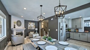 A modern kitchen with grey cabinets, a built-in oven, and a dining area with a wooden table set for four. - Luxurious & Forested Oasis in Flagstaff w/ Hot Tub (Flagstaff)