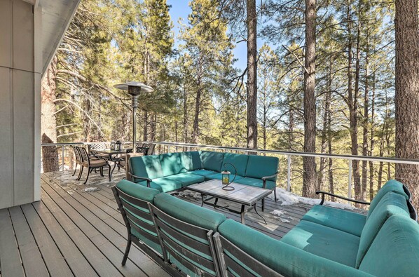 A wooden deck with a green sofa, a table, and chairs.