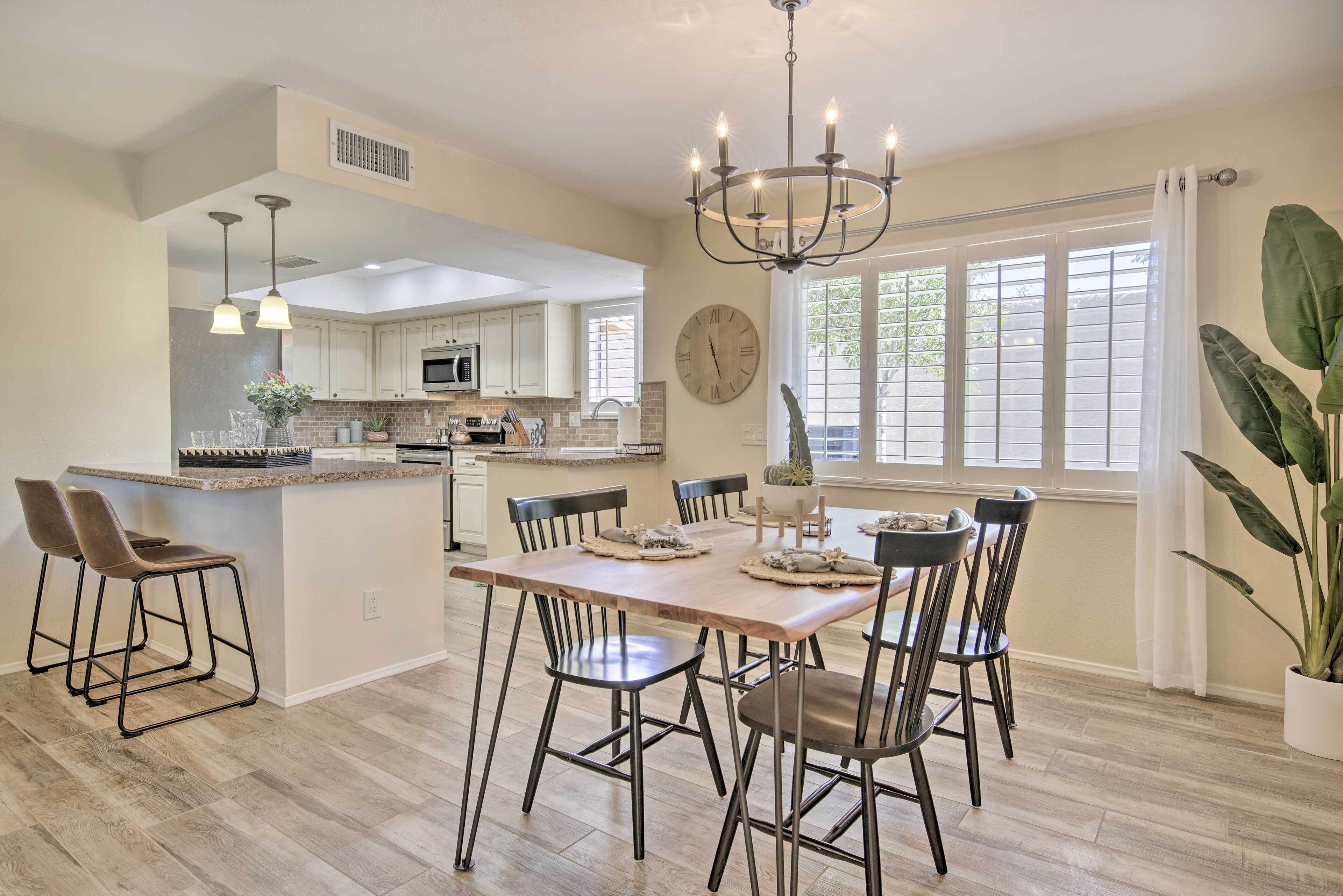 A spacious kitchen with a central island, modern bar stools, and a chandelier.