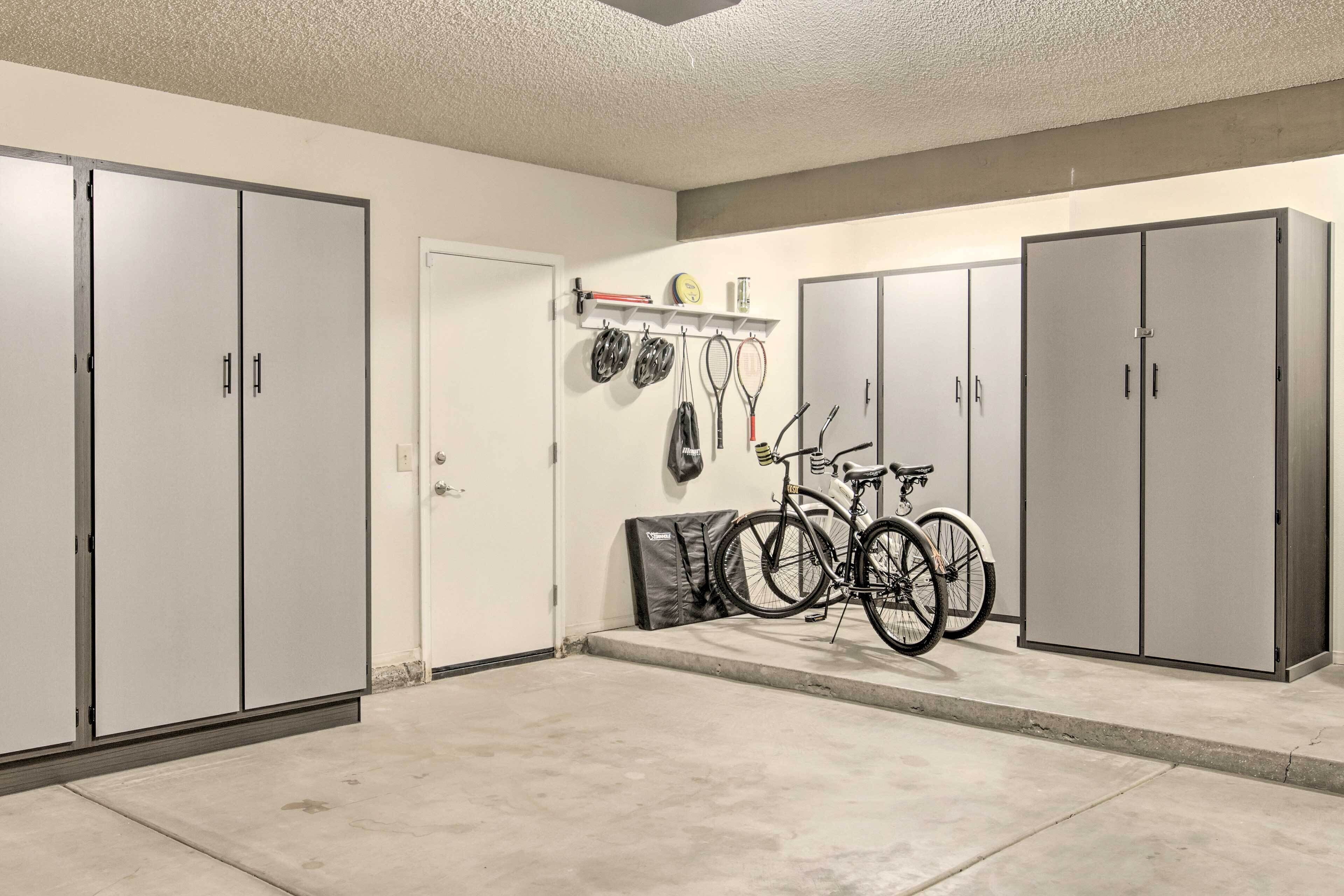 Un garage avec deux armoires grises, un vélo et des raquettes de tennis accrochées au mur.