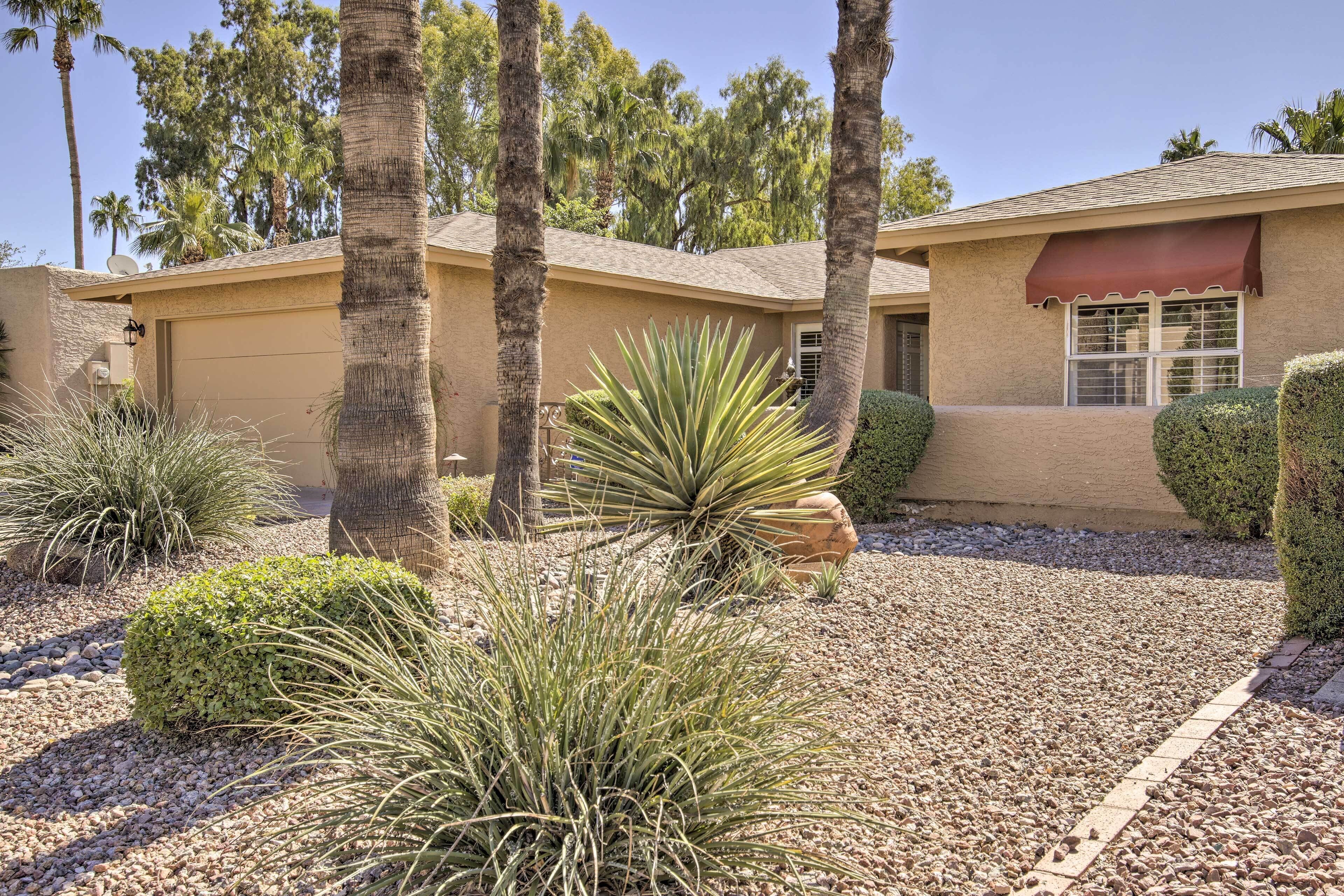 A house with a beige exterior, a red awning over the front door, and a gravel driveway.