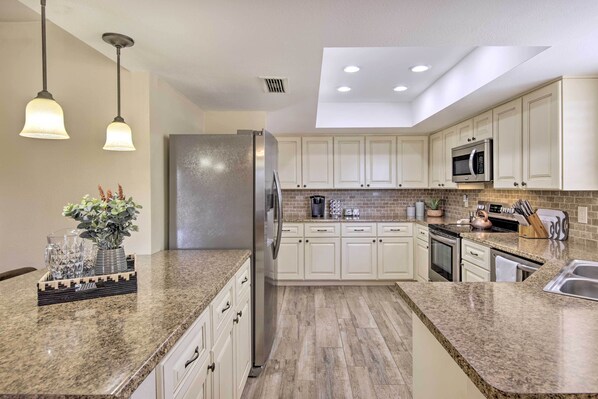 A modern kitchen with granite countertops, stainless steel appliances, and white cabinetry.