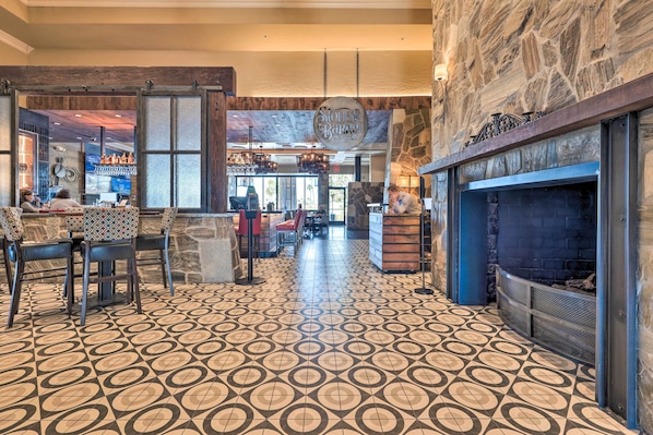 A restaurant with a patterned floor, stone walls, and a bar area. - Stunning Sun Lakes Home w/ Beautiful Lake Views! (Chandler)