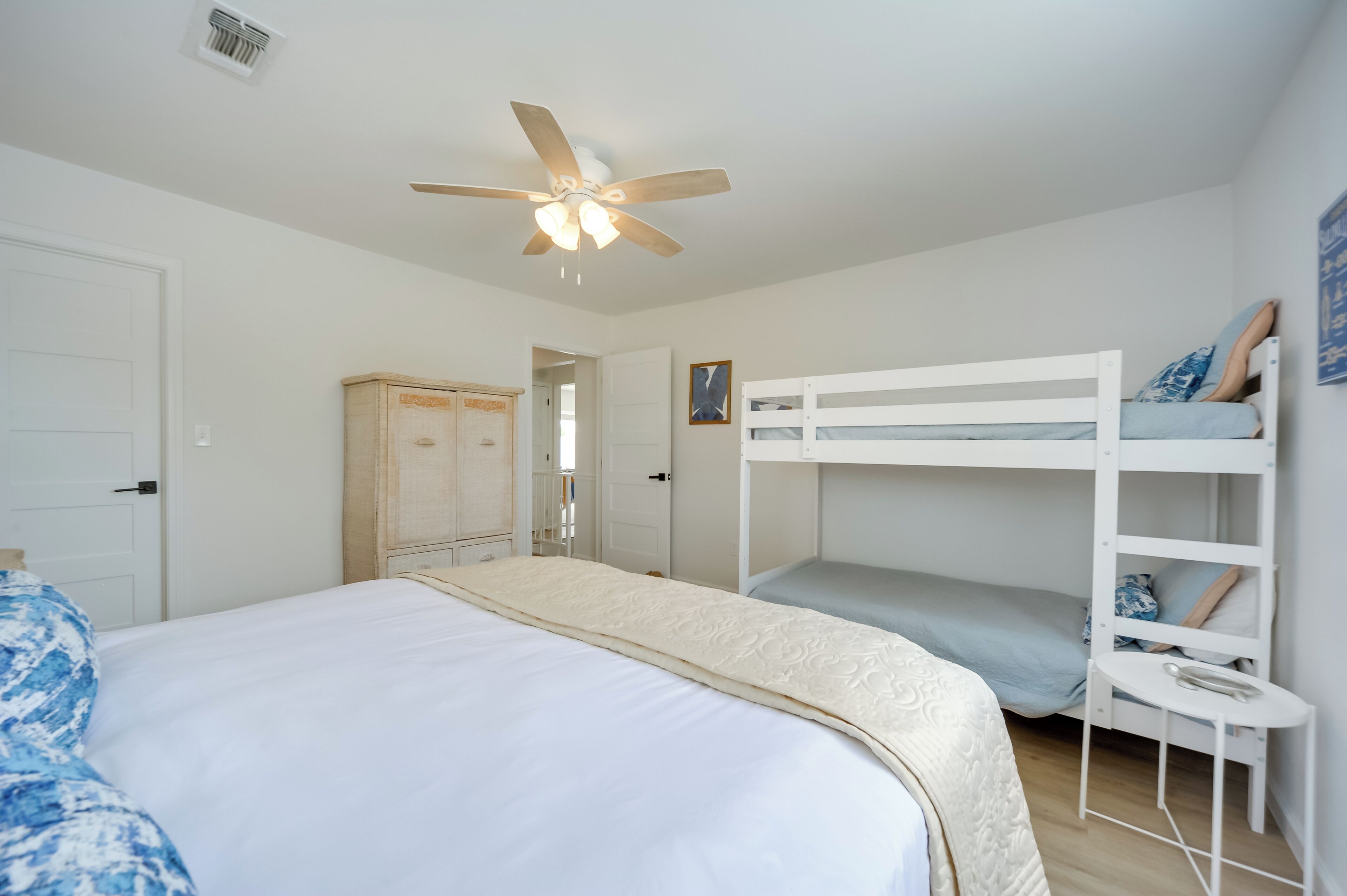 A bedroom with a bunk bed, a ceiling fan, a wardrobe, and a door.