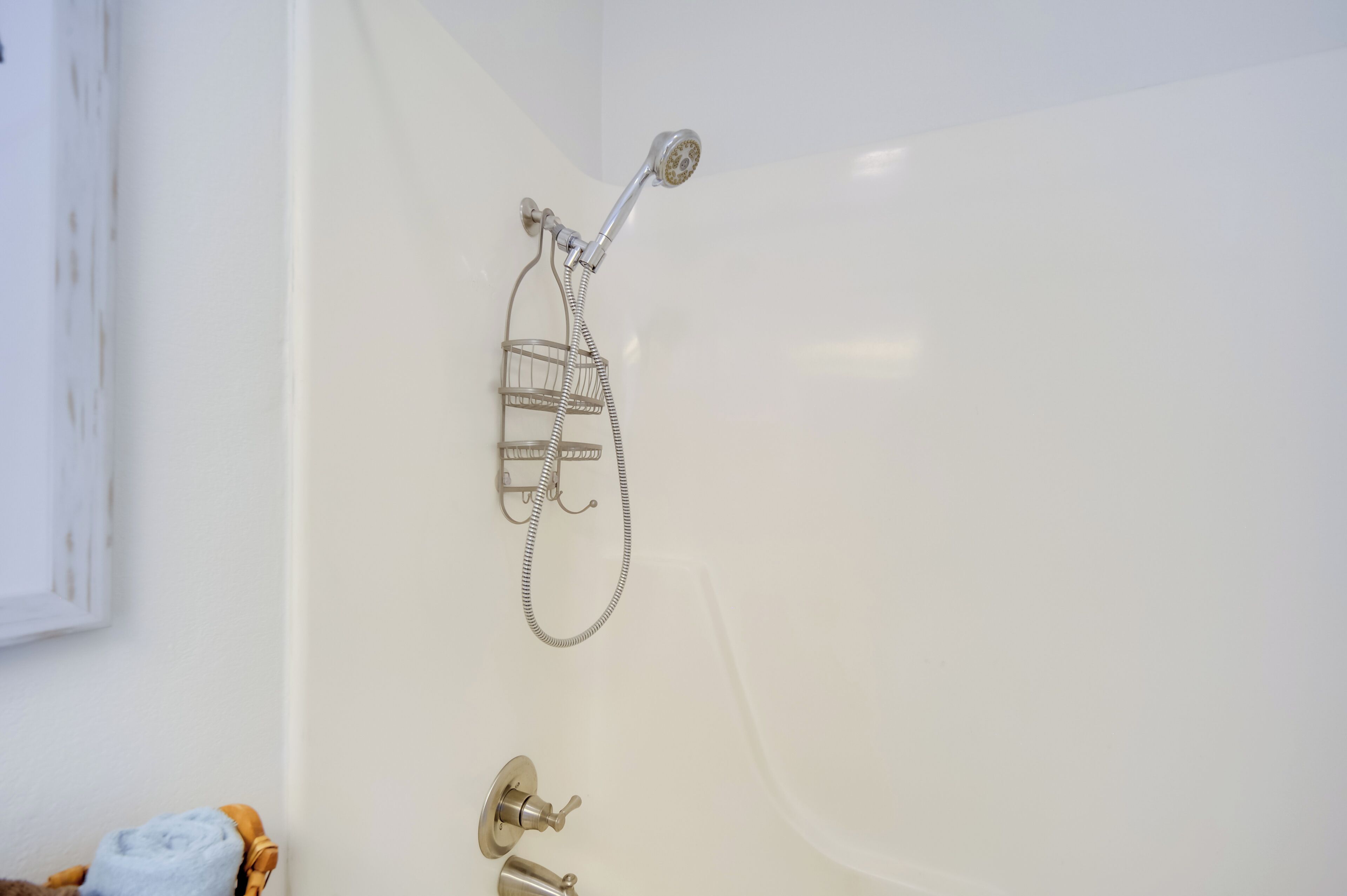 A bathroom with a white bathtub, a showerhead, and a towel rack.