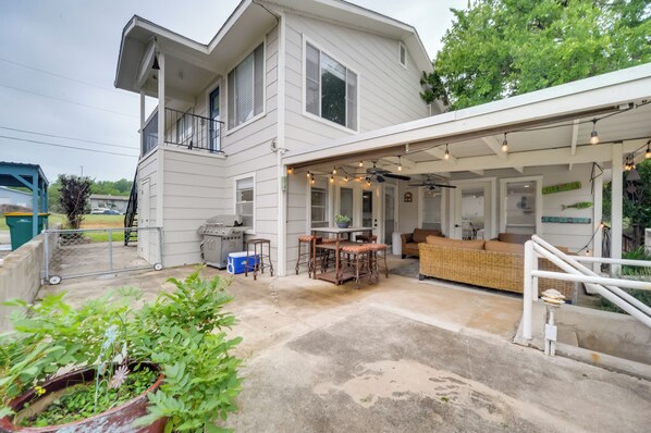 A two-story house with a covered patio, outdoor seating, and a small garden area.