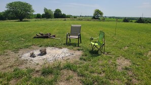 Un campo cubierto de hierba con dos sillas y un tronco.