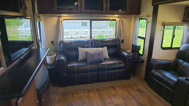 Interior acogedor de una caravana, con un sofá de cuero, una cafetera y una ventana con vistas al exterior.