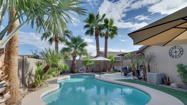 A swimming pool with palm trees, a covered patio, and a clock on the wall. - Maricopa Retreat w/ Peaceful Backyard Oasis! (Maricopa)