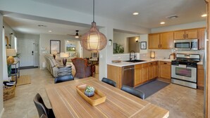 A modern kitchen with wooden cabinets, stainless steel appliances, and a dining area with a wooden table and chairs. - Maricopa Retreat w/ Peaceful Backyard Oasis! (Maricopa)