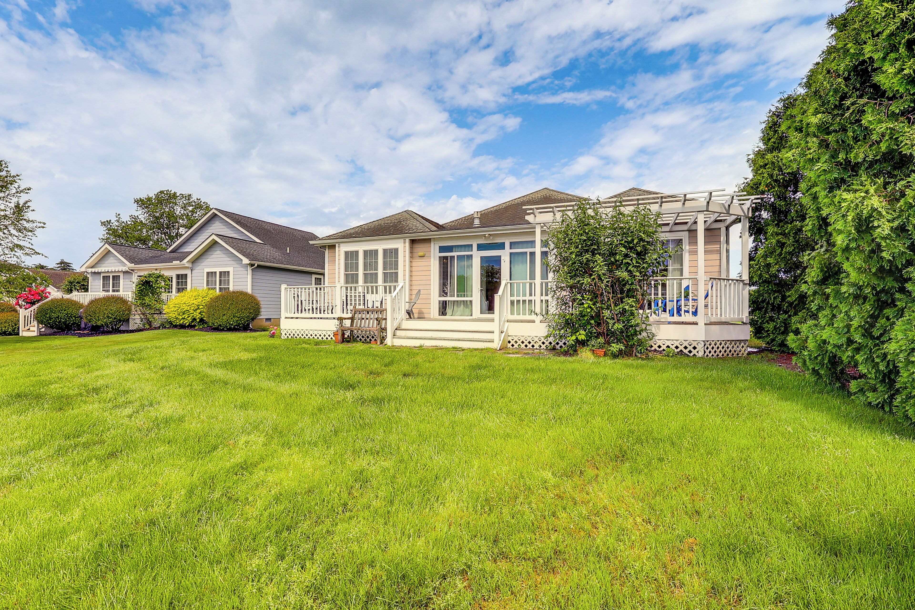 A residential house with a well-maintained lawn, a porch with a railing, and a covered entryway.