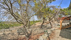 A stone pathway leading to a wooden structure with a bench and a tree. - Charming Ingram Home w/ Yard & Furnished Patio! (Ingram)