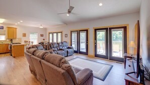 Ein geräumiges Wohnzimmer mit einem großen braunen Ecksofa, einem Deckenventilator und einem Essbereich mit Holzsesseln.