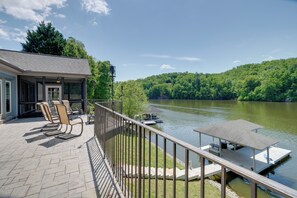A lakeside deck with outdoor seating and a dock extending into the water. - Waterfront Smith Mountain Lake Home w/ Boat Dock! (Goodview)