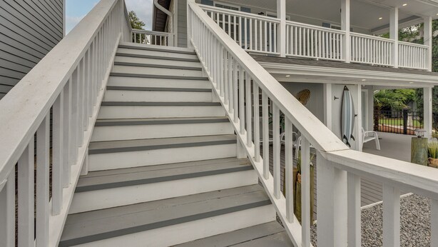 A staircase leading to a covered upper deck with railings and a view of the surrounding area. - Sun, Sand & Smiles! Ocean Isle Apt w/ Balcony (Ocean Isle Beach)